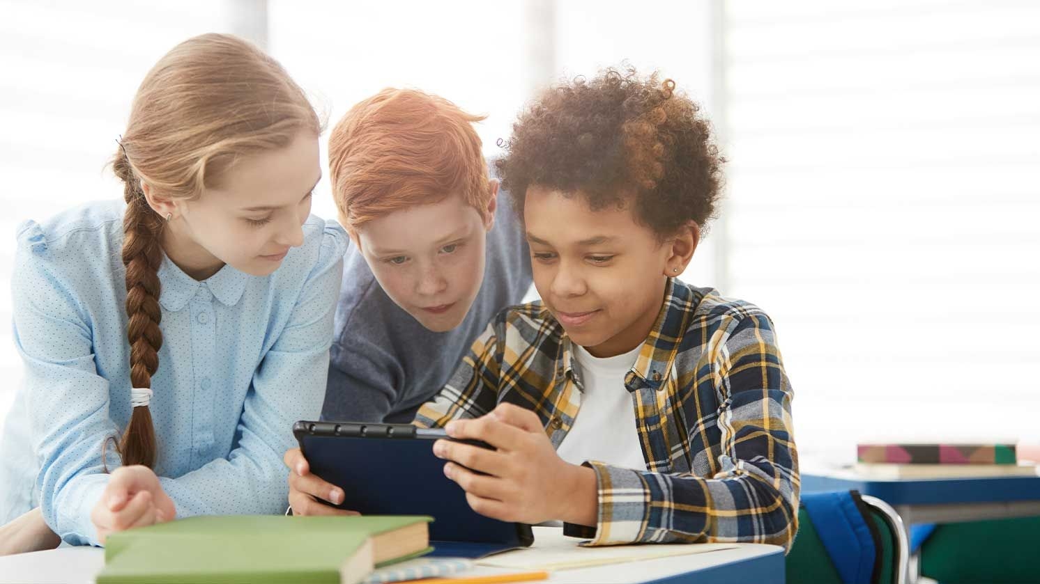 Drei Schüler(innen) gemeinsam an einem Tablet